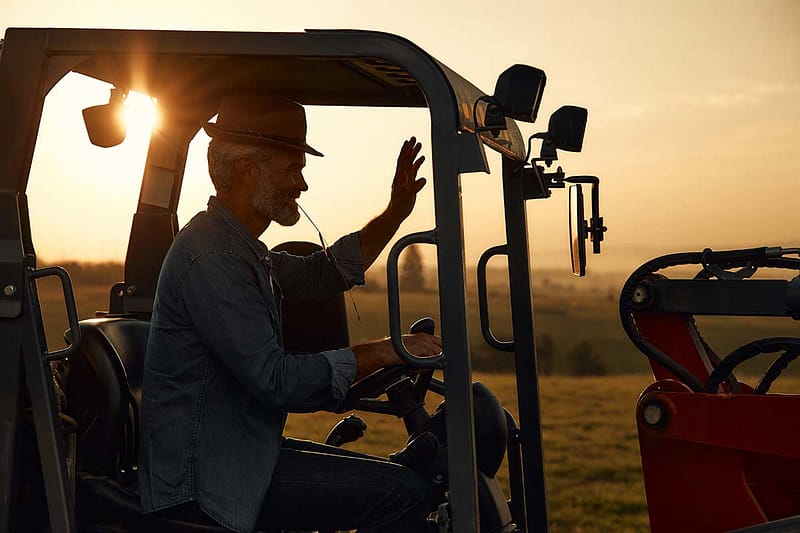 Man driving a small gasoline powered tractor in an agricultural setting.